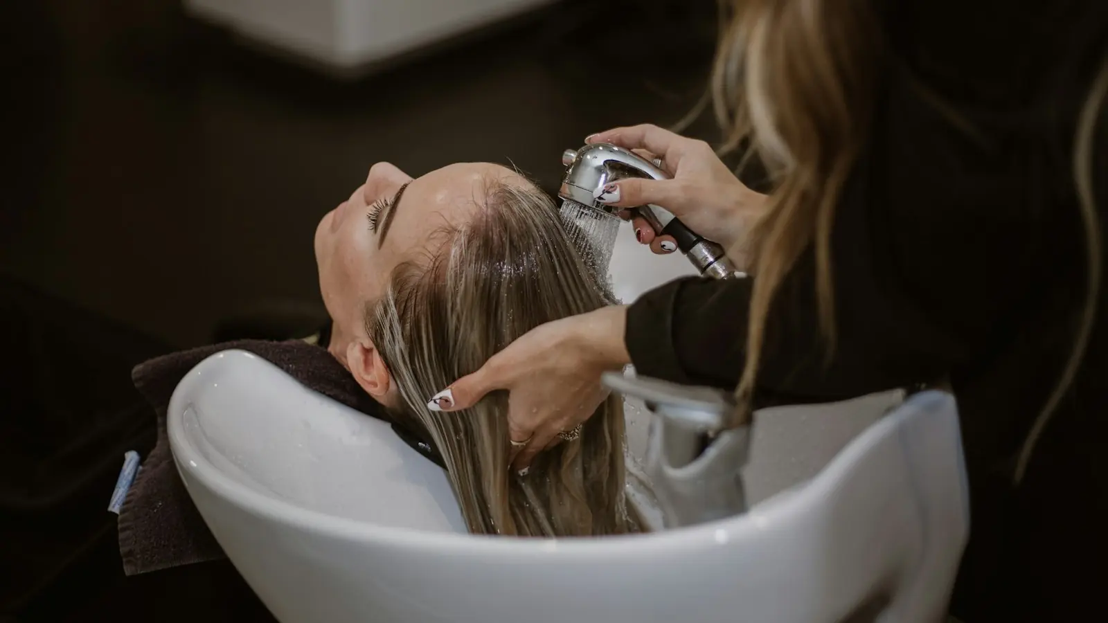 A client having her hair washed at the shampoo bowl
