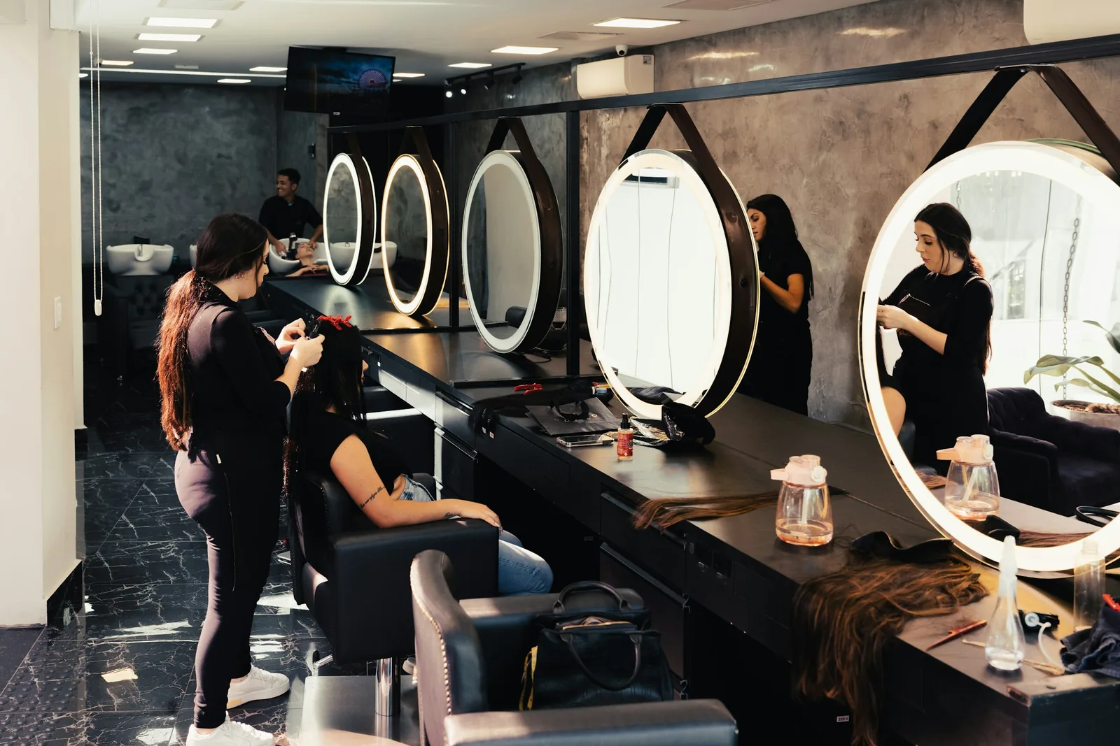 Stylists working on clients at their stations on a salon floor