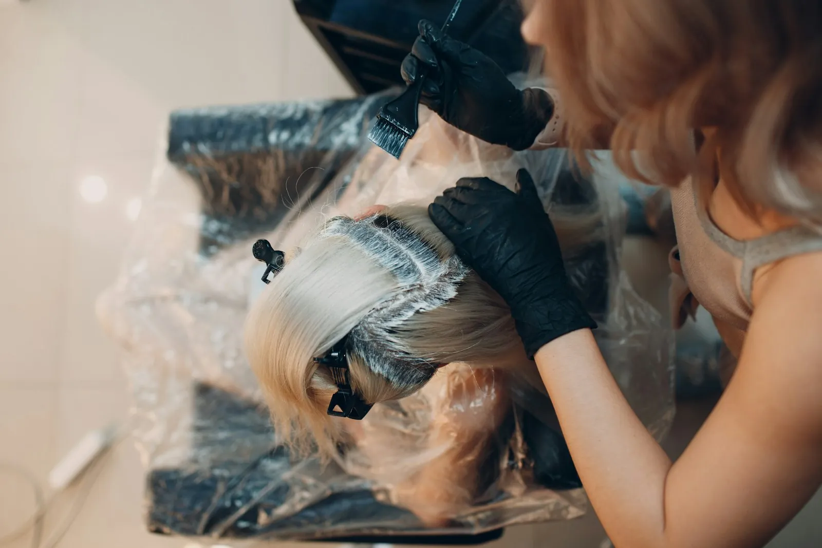 A colorist in black gloves painting foils into a client's hair