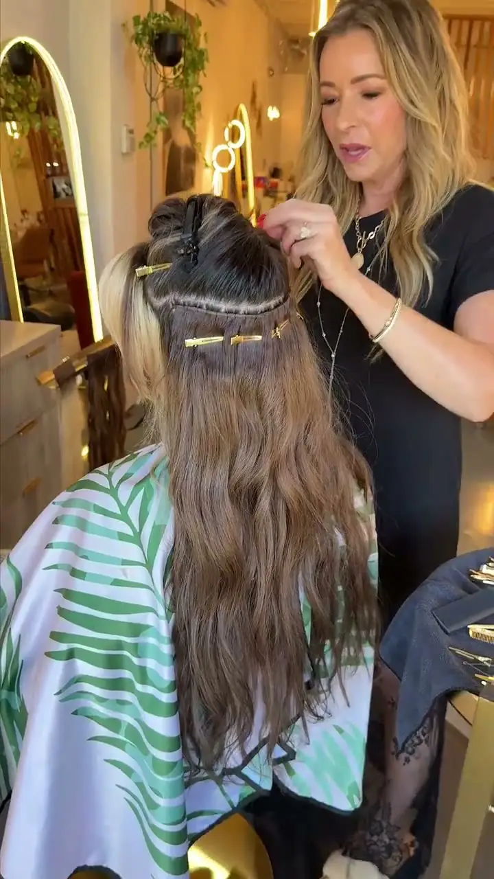 Alisa Pose installing hair extensions on a client
